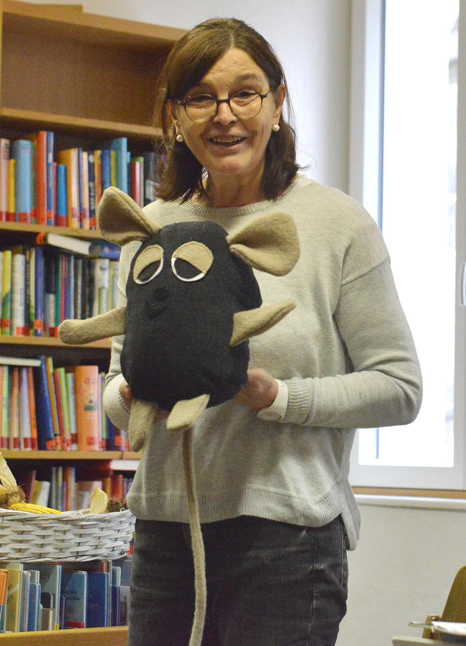 Stehende Frau mit Maus-Handpuppe in beiden Händen