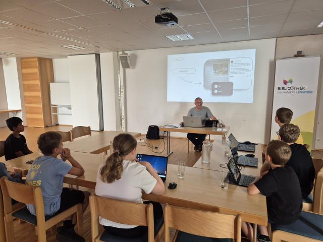 Kinder vor PC und Laptop schauen sich eine Powerpoint-Präsentation an