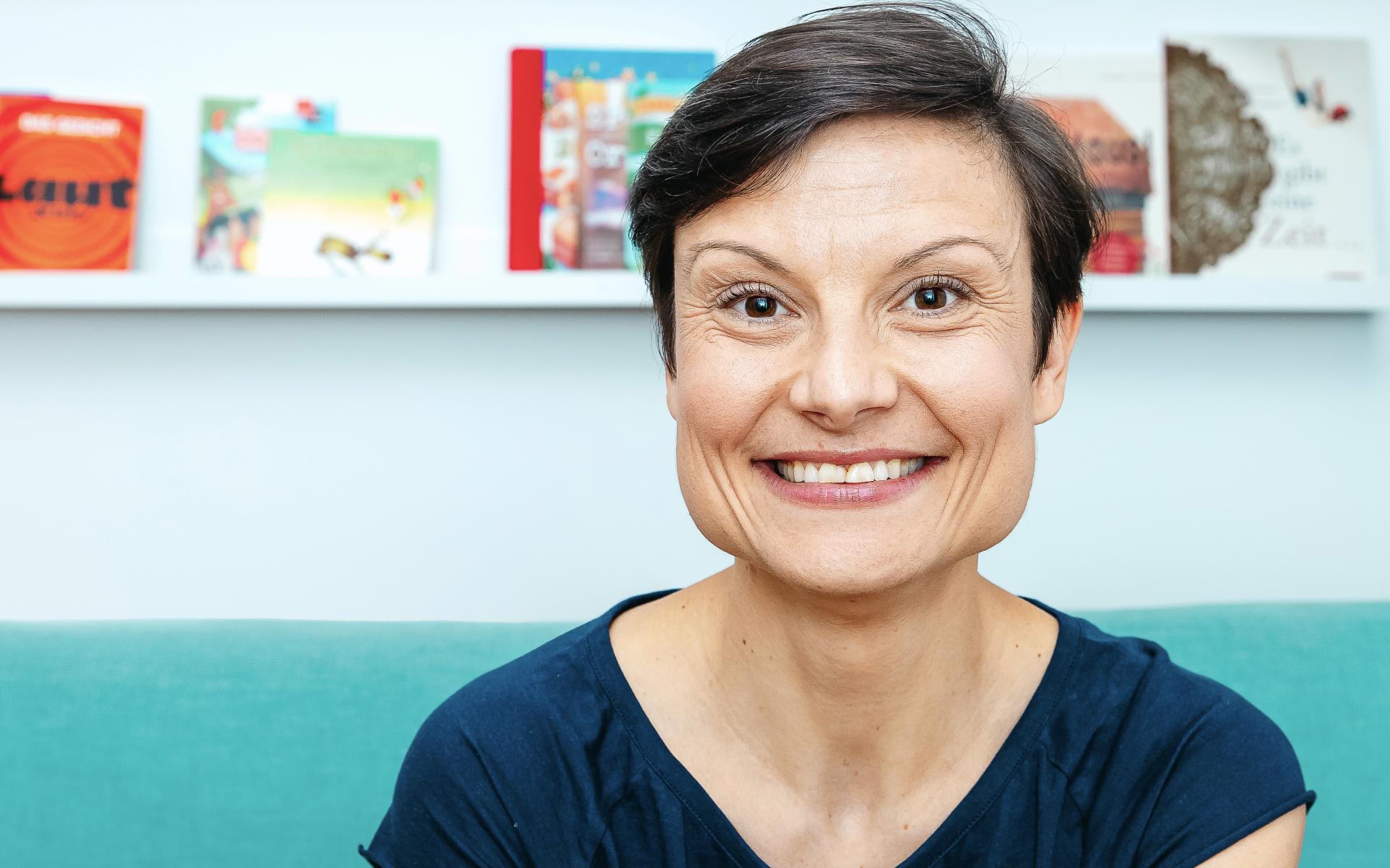 Frau auf Sofa sitzend vor Bücherregal